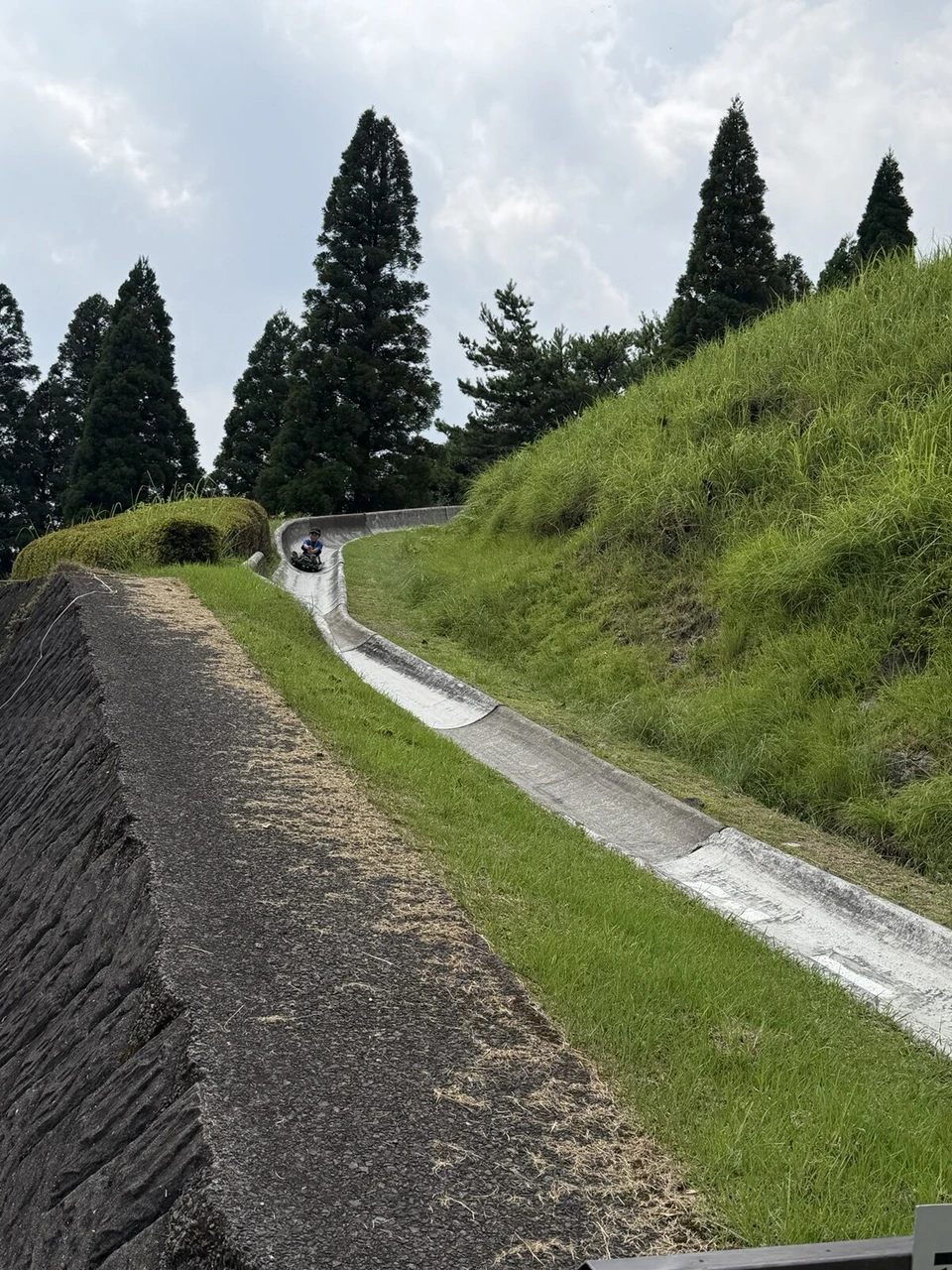 霧島神話の里公園の、草の土手に沿ってカーブしながら下っていくスーパースライダーのコース