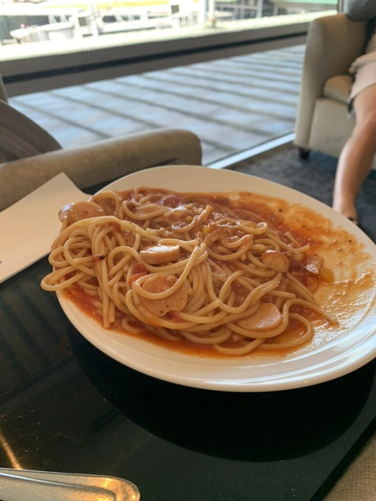 KLIAゴールデンラウンジのトマトソースのスパゲッティ。奥に椅子と窓