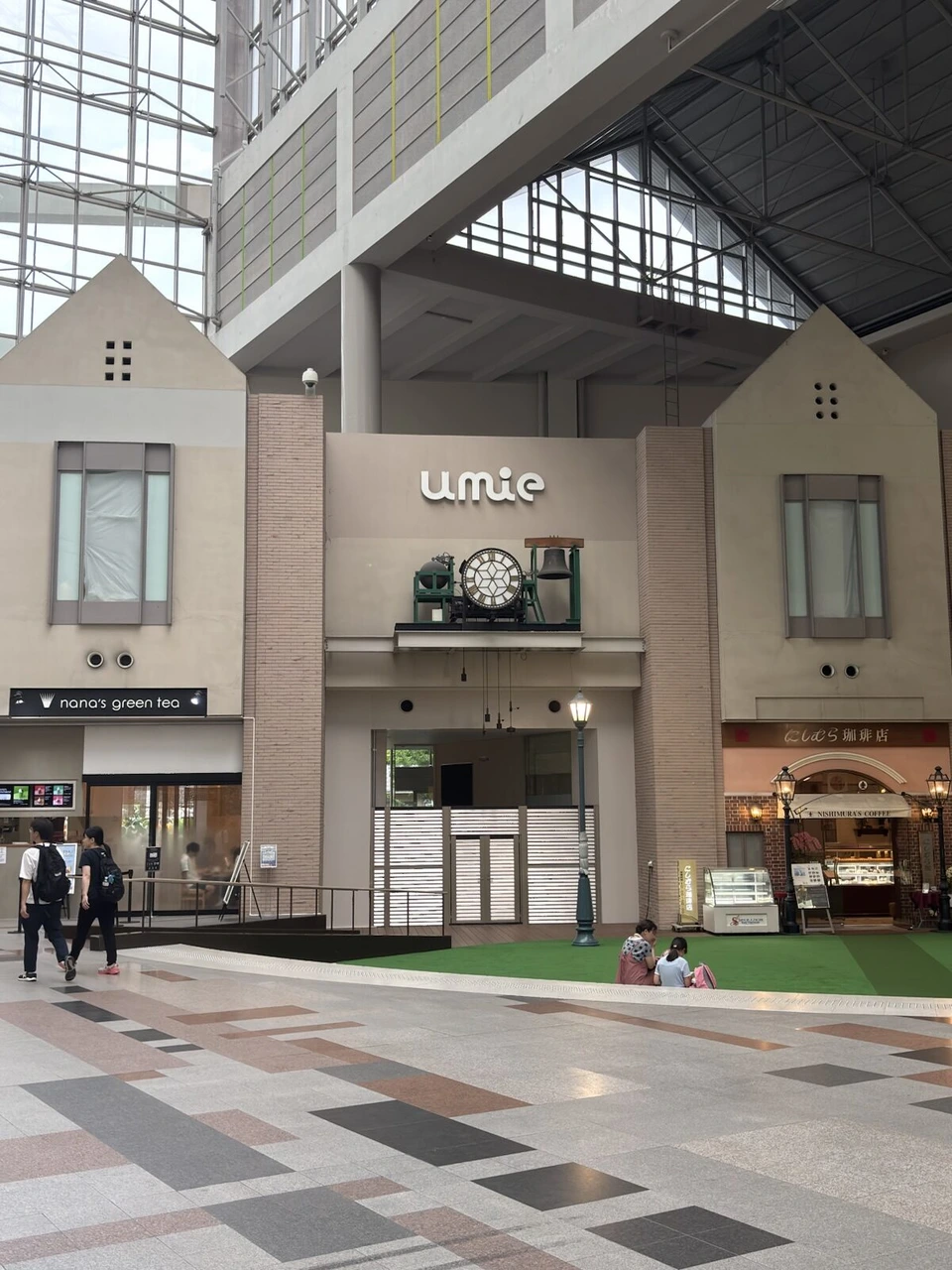 神戸ハーバーランドumieの吹き抜けの広場。三角屋根の建物風の壁にumieのロゴと大きな時計