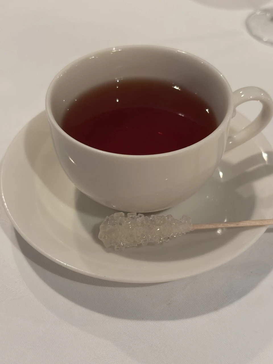 ディナークルーズの最後に出た、白いカップの紅茶とソーサーに添えられたスティックシュガー