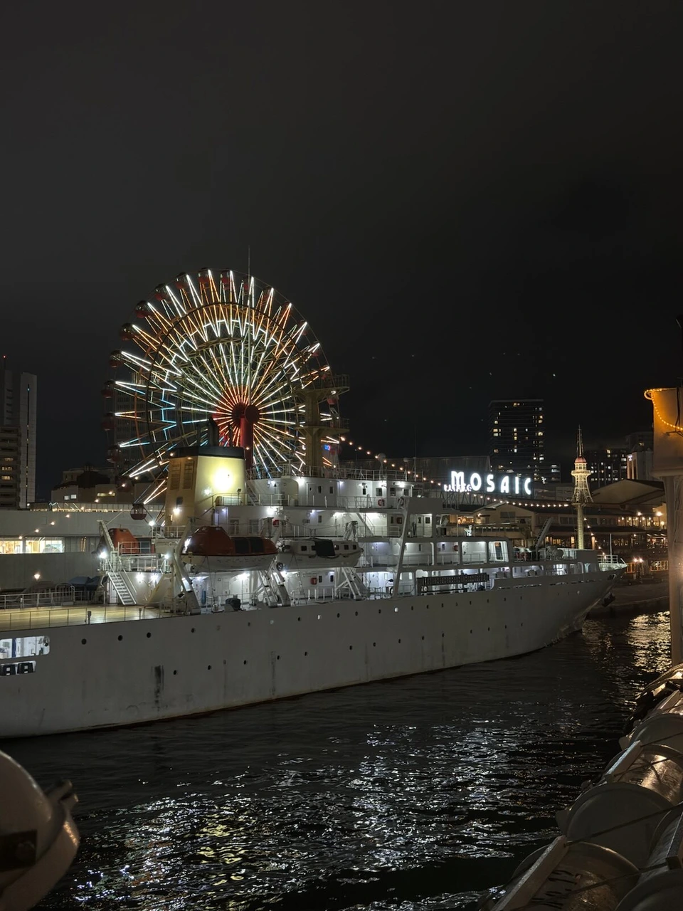 夜のハーバーランド。青く光る観覧車と、モザイクの岸壁に停泊した白い大型船