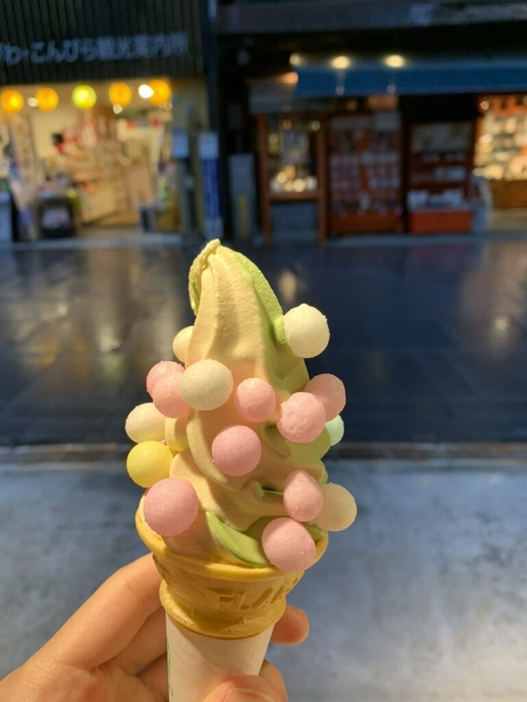 雨の参道で持つあられのせソフトクリーム。奥に「かがわ・こんぴら観光案内所」