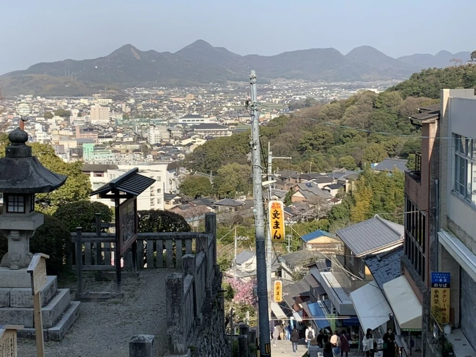 金刀比羅宮の石段の上から見た琴平の町と、ぎざぎざした山並み。石灯籠と参道の店の屋根