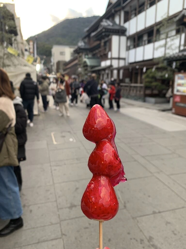琴平の表参道で買ったいちご飴。奥に参道の旅館の建物