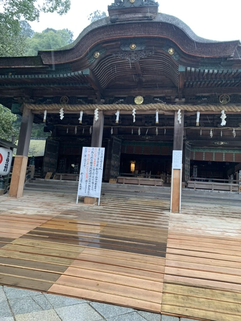 雨に濡れた板張りの前に建つ、金刀比羅宮の唐破風の大きな社殿