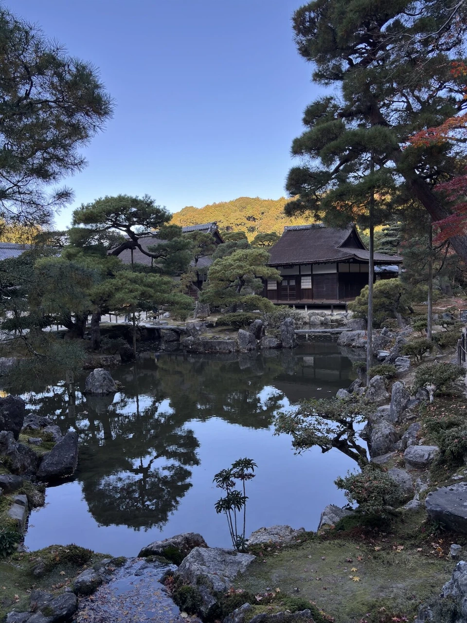 銀閣寺の池に映る松と青空、池の向こうに建つお堂
