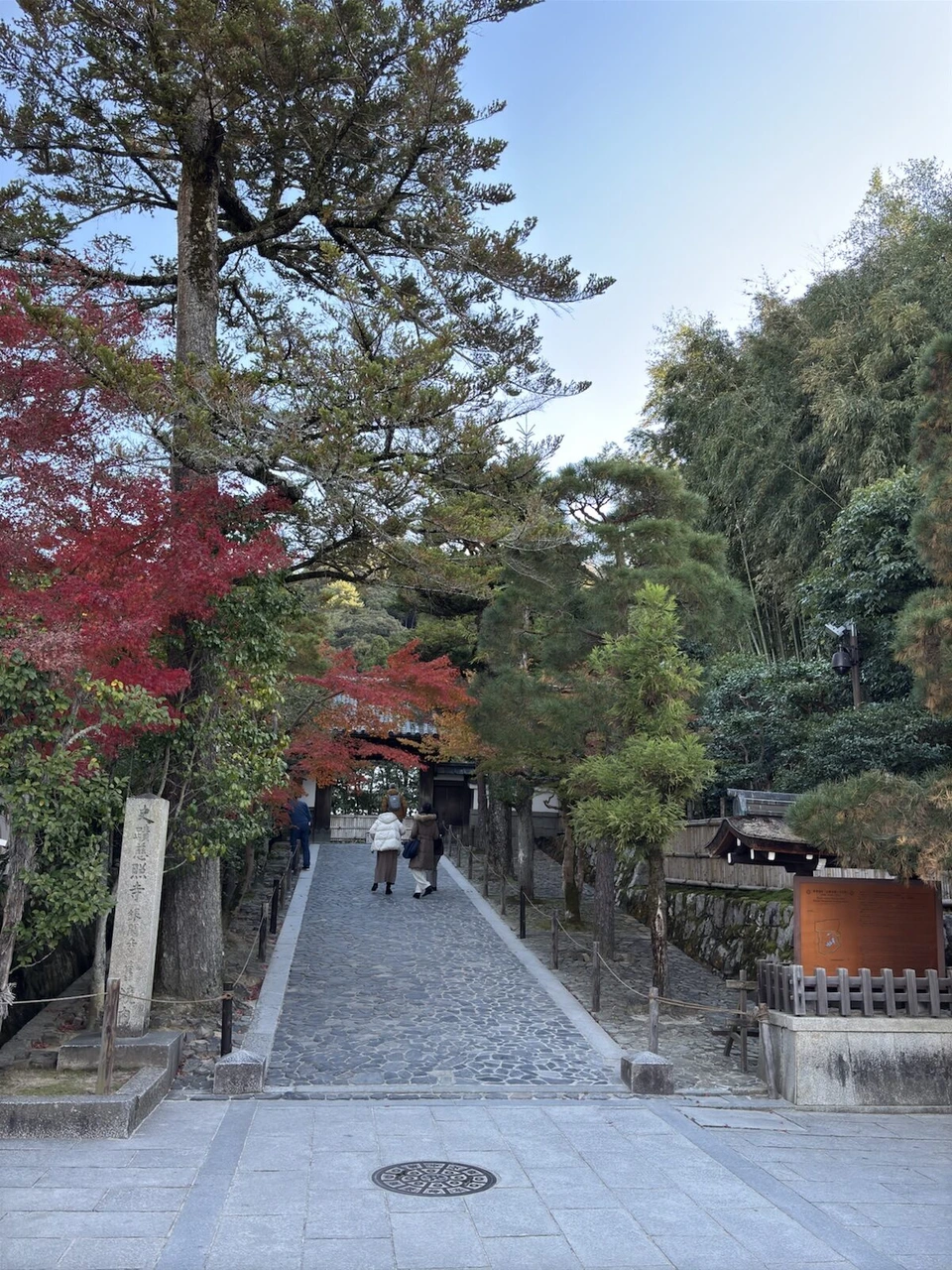 銀閣寺の参道の入口。石柱と石畳、左手に赤い紅葉