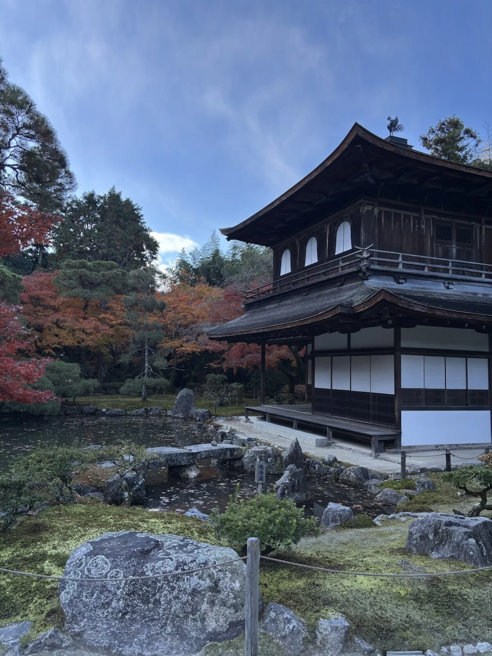 池越しに見た銀閣寺の観音殿。2階建ての木造の建物と、まわりの紅葉