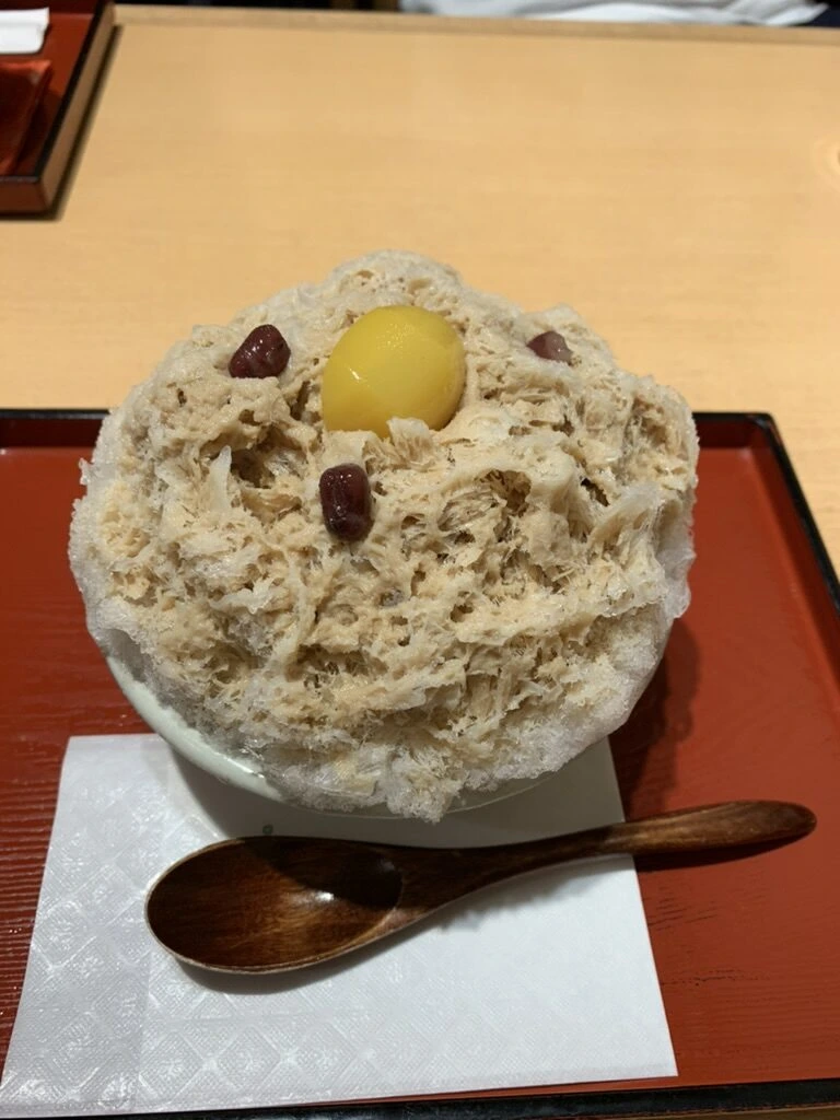 祇園の甘味処の、栗の甘露煮と小豆がのった茶色いかき氷と木のスプーン