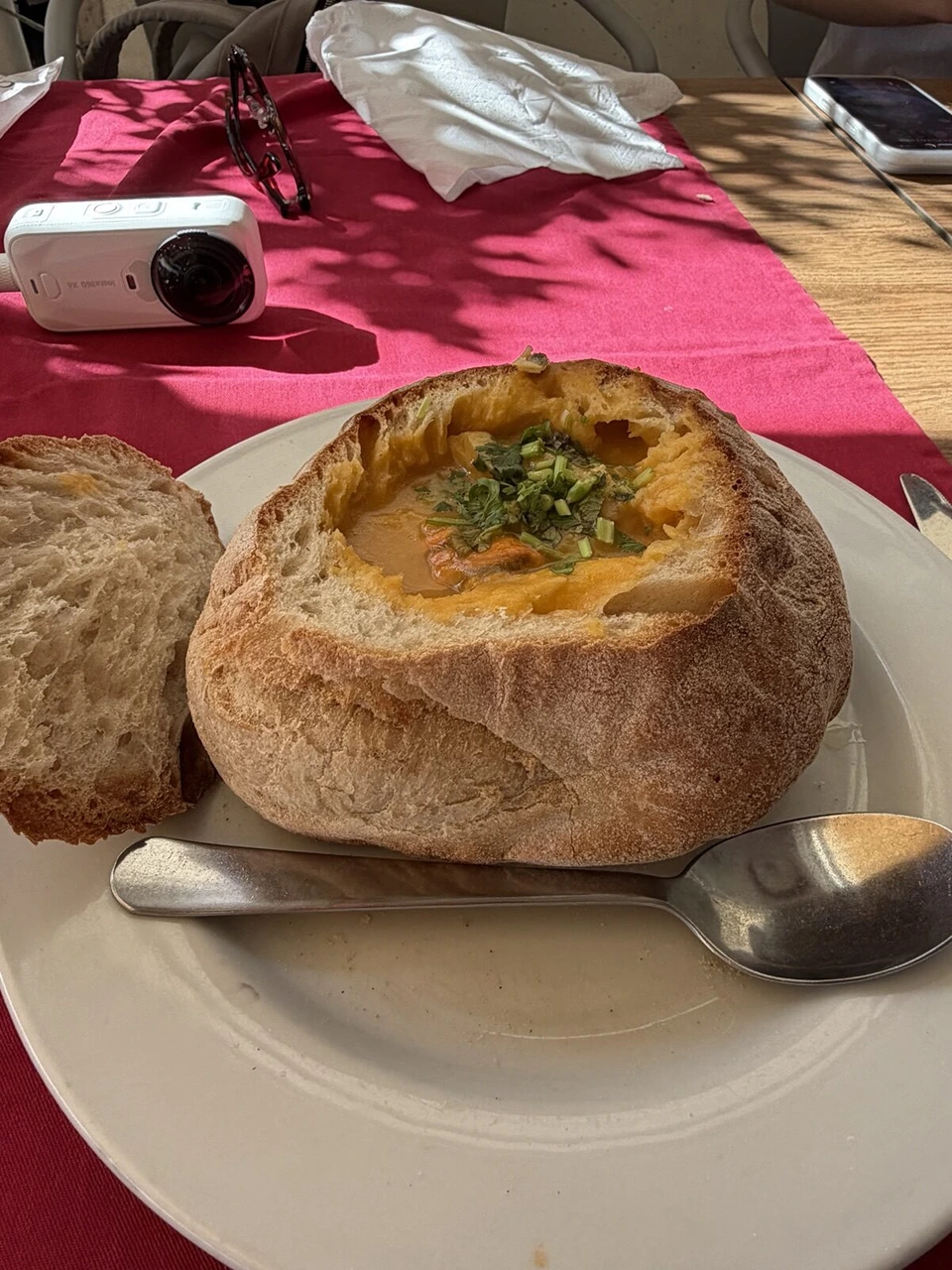丸いパンをくりぬいた器に入ったオレンジ色のスープ