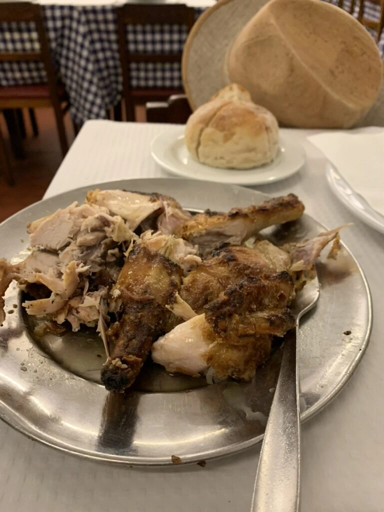 ロシオ広場近くのレストランの、金属の皿に盛られたローストした肉とパン