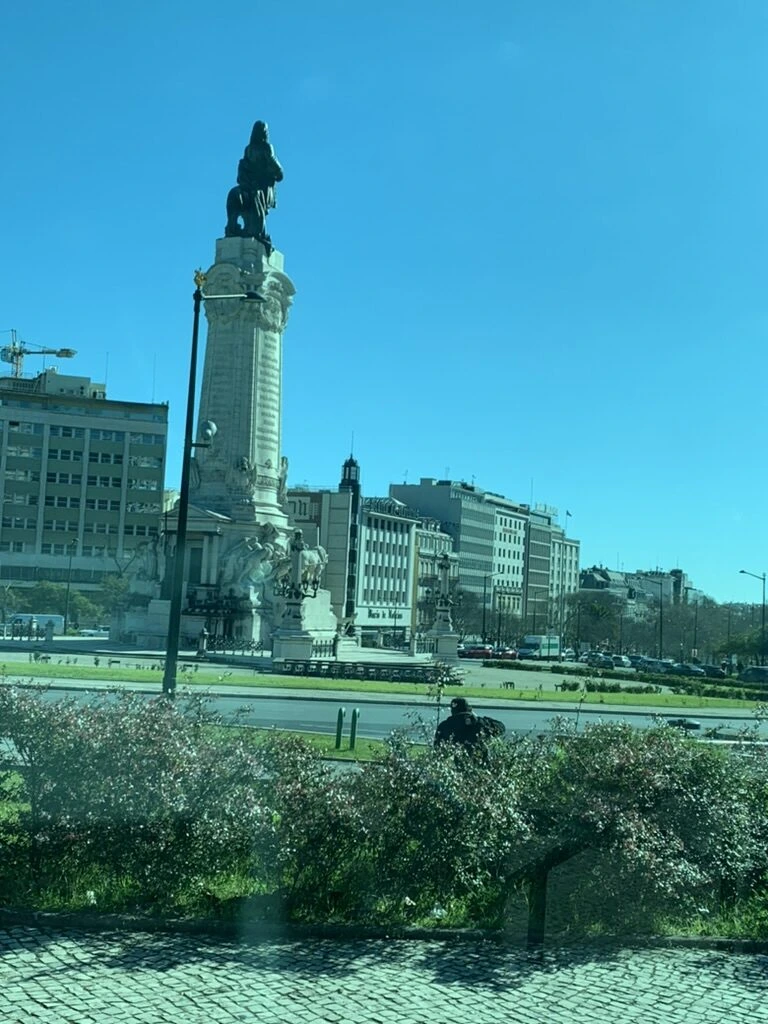 リスボンの植え込みの向こうに見えるポンバル侯爵広場の記念塔