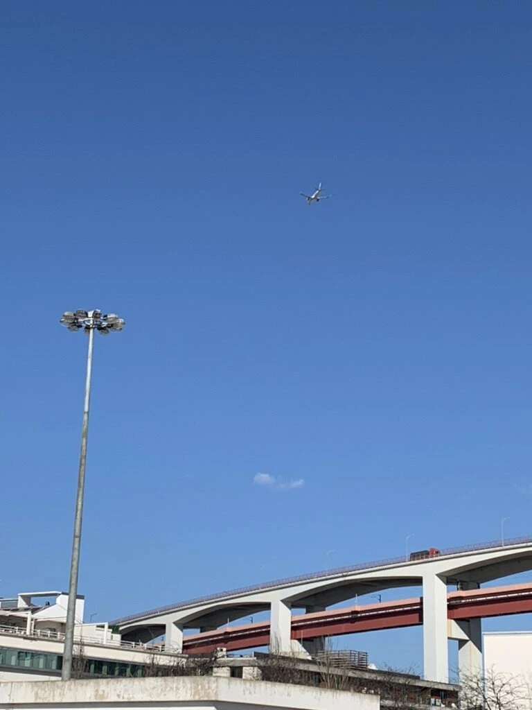 リスボンの青空の下の4月25日橋と、上を飛ぶ飛行機
