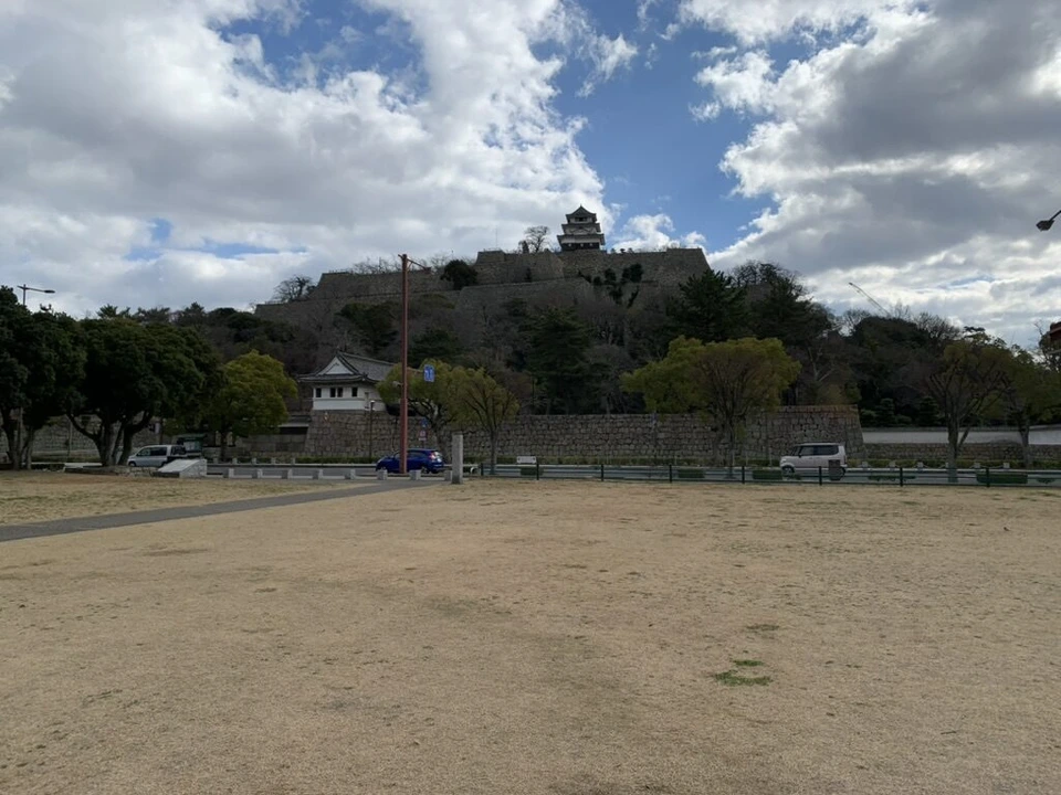 丸亀城の下の広場から見た、石垣が重なる城山と頂上の天守