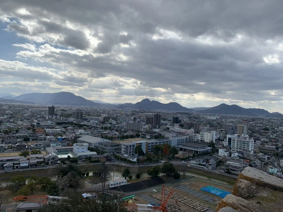 丸亀城の本丸から見た市街地と山並み、雲の多い空