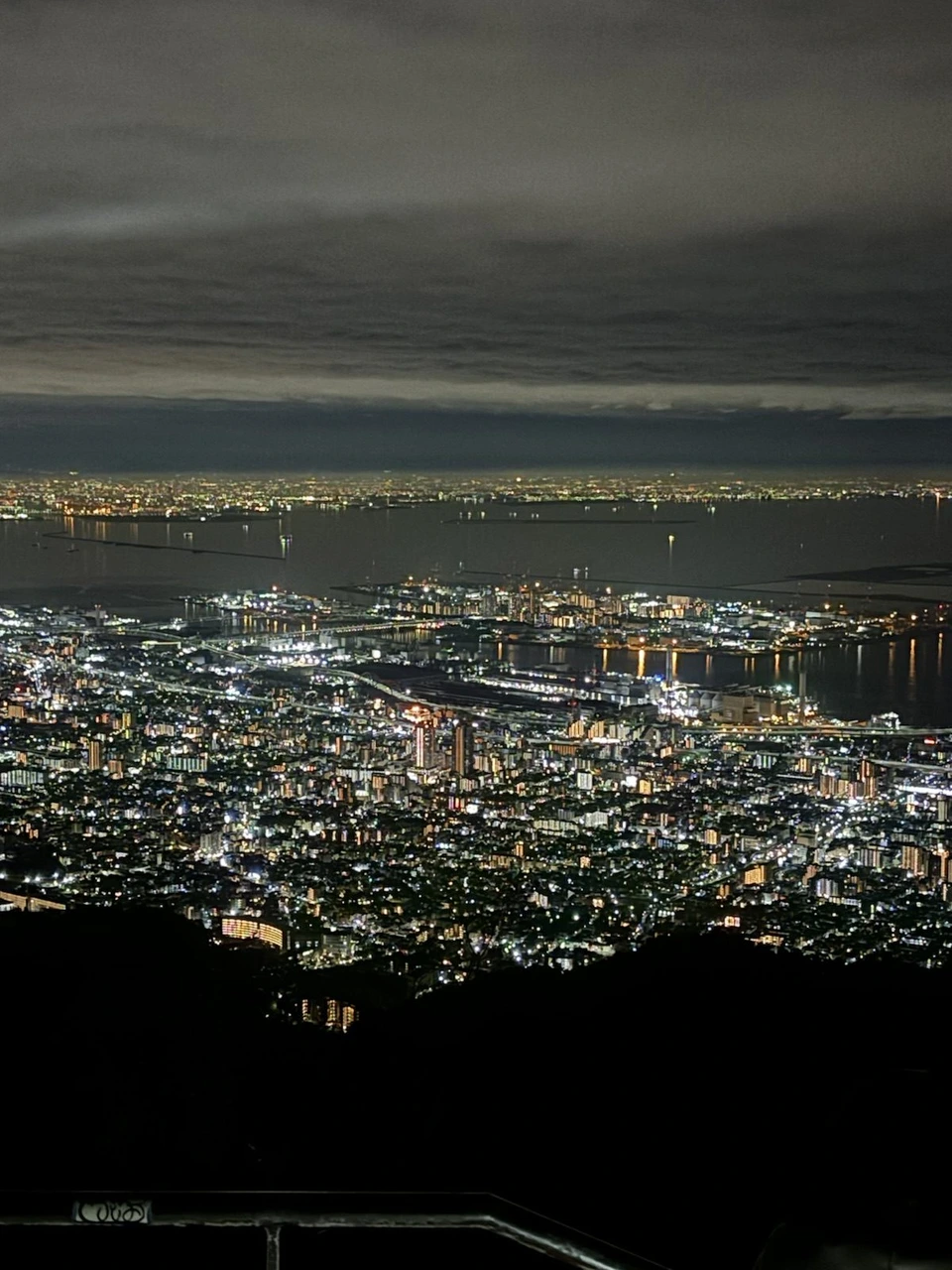 掬星台から見た神戸の街と港の夜景。手前に住宅やビルの明かり、奥に港と海、海の向こうにも街の明かり