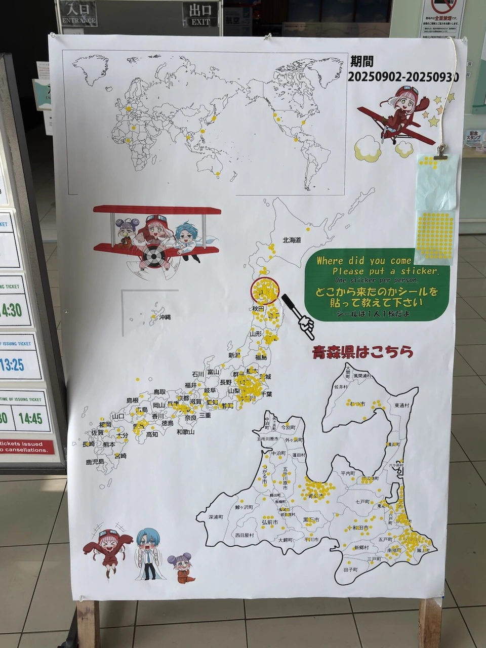 三沢航空科学館の入口の、世界地図と日本地図、青森県の地図に黄色い丸シールがたくさん貼られた掲示板