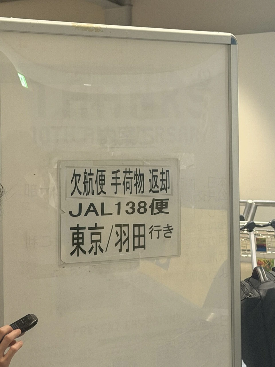 伊丹空港の手荷物受取所に立てられたホワイトボード。欠航便 手荷物返却 JAL138便 東京/羽田行きと書いた紙が貼ってある