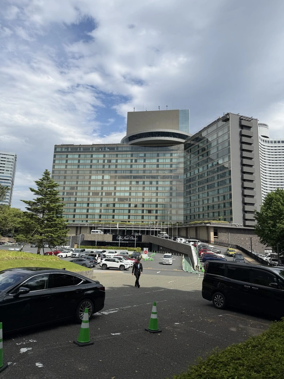 ホテルニューオータニ(東京)の外観。ガラス張りの本館と丸い屋上の建物、手前に車寄せと駐車場