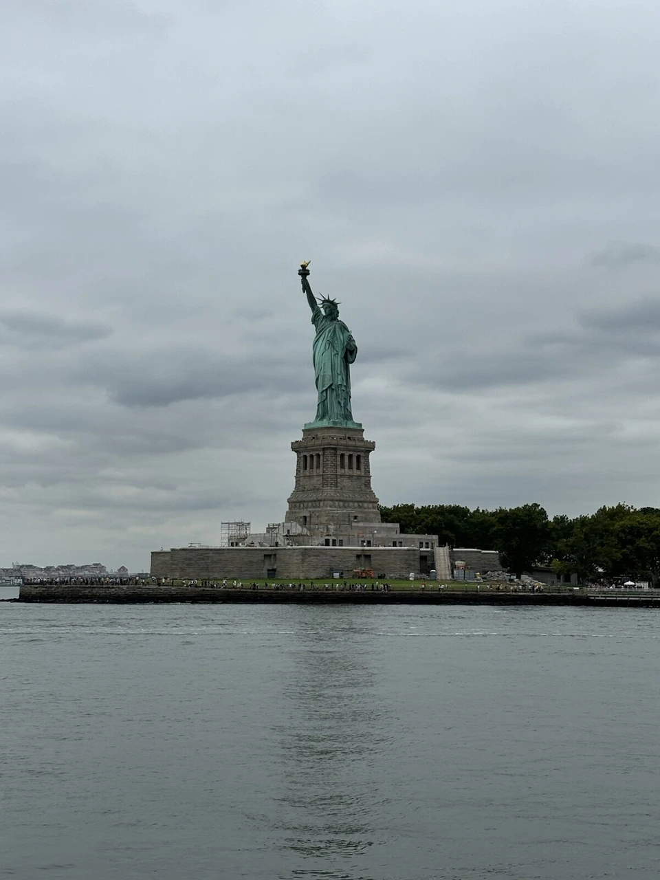 Freedom Libertyクルーズの船から見た、曇り空の下の自由の女神とリバティ島