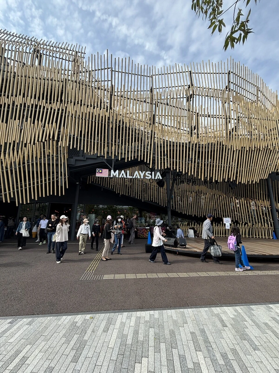 細い木の格子が波打つように重なったマレーシア館の外観と、MALAYSIAの文字