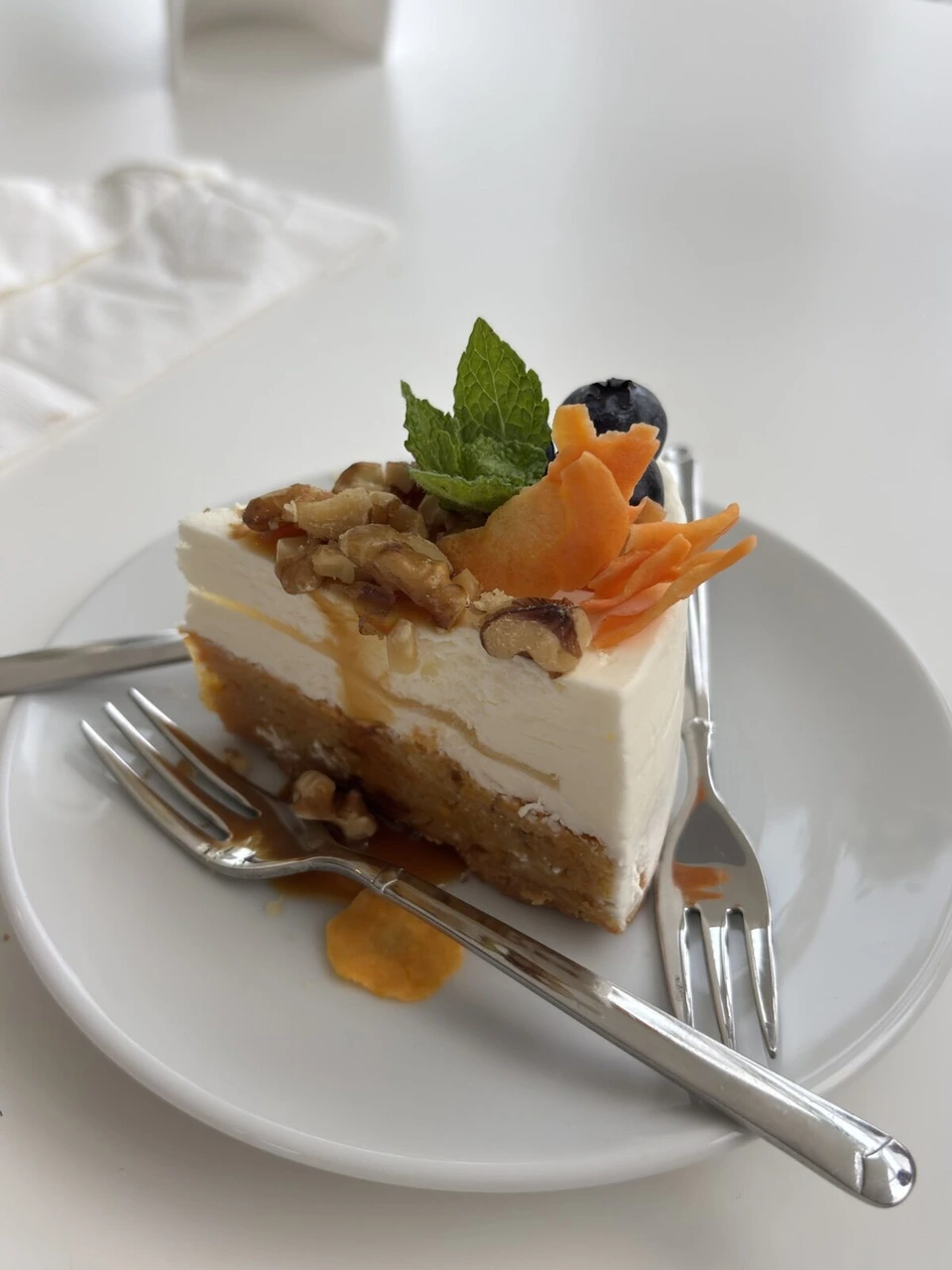 スイス館のカフェのケーキ。白いクリームの層にナッツ、ブルーベリー、ミントの葉