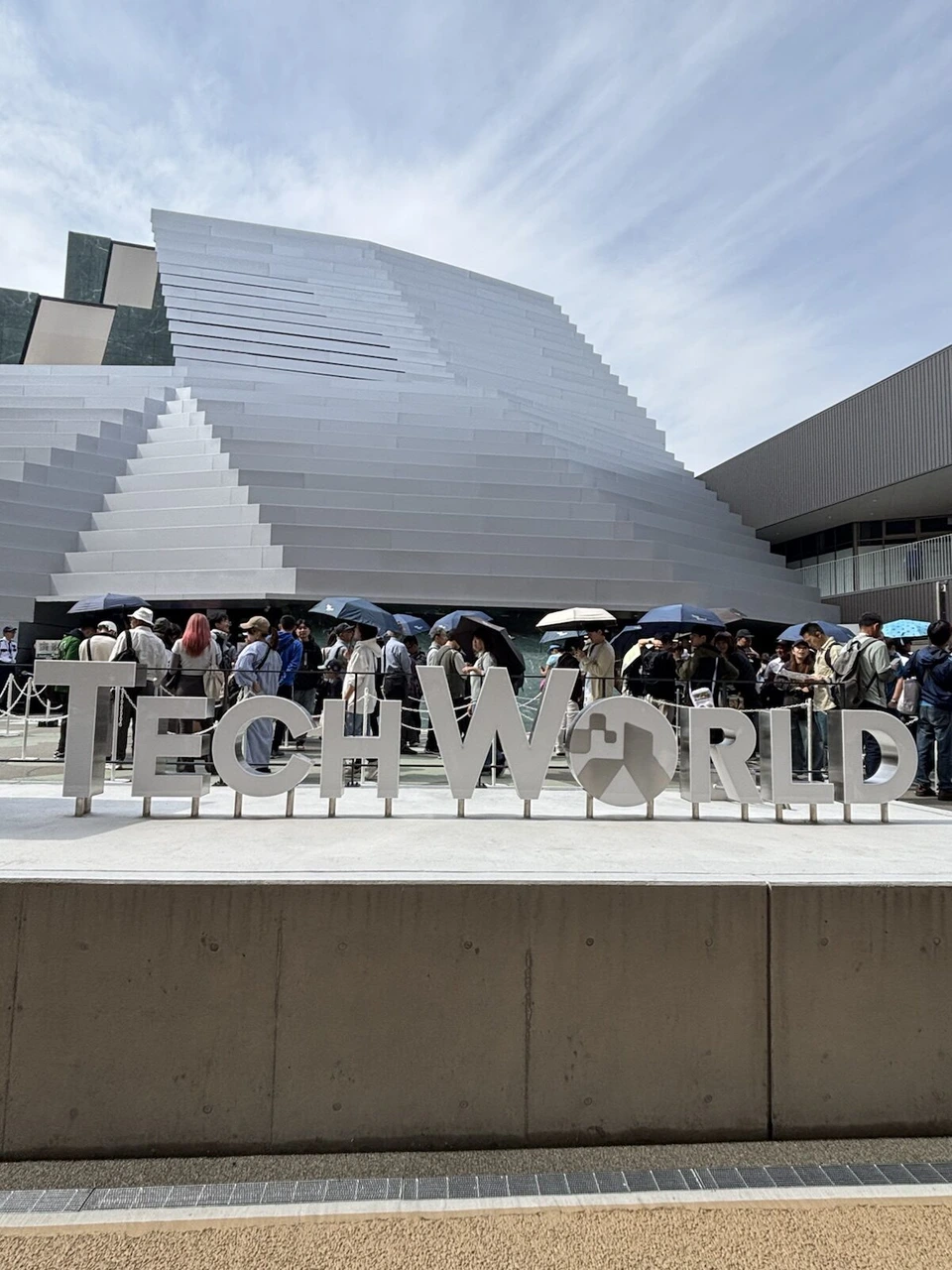 大阪・関西万博のTECH WORLD館。白い段々の外壁と立体文字、壁沿いの行列