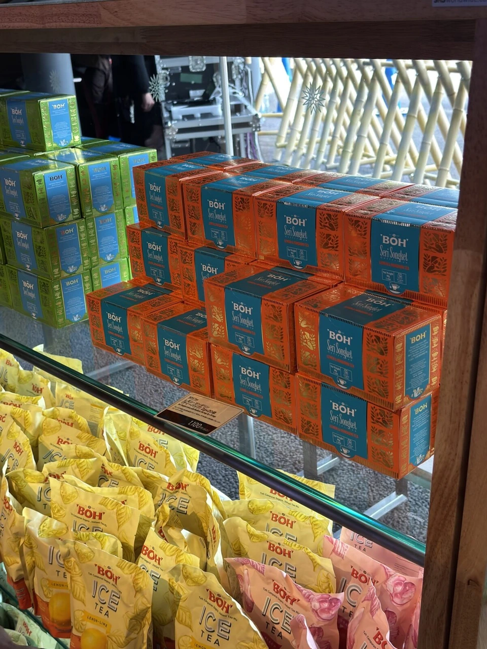 マレーシア館のショップの棚に積まれた青い箱のお土産と、黄色い袋のお菓子