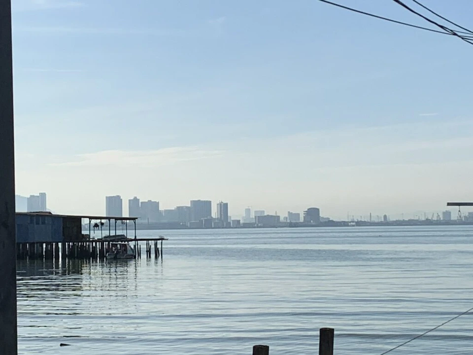 タン・ジェティの桟橋の先から見た朝の海と、左の水上家屋