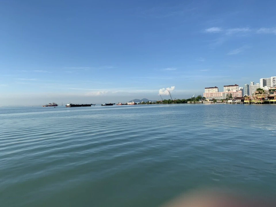 タン・ジェティの先から見た朝の海と、右側に続くジョージタウンの海岸の建物
