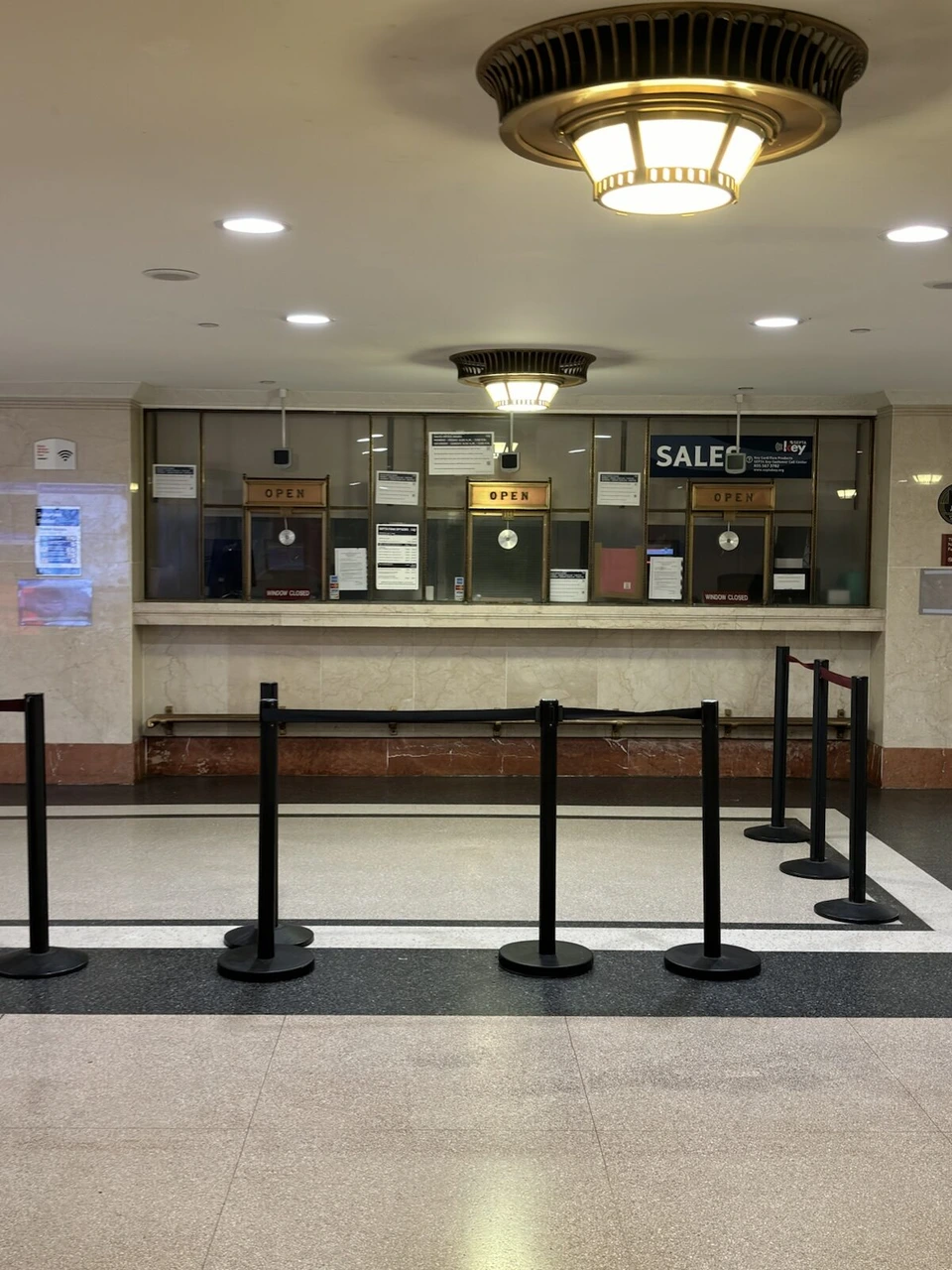 サバーバン駅のきっぷ売り場と、ロープで仕切られた通路、丸い照明
