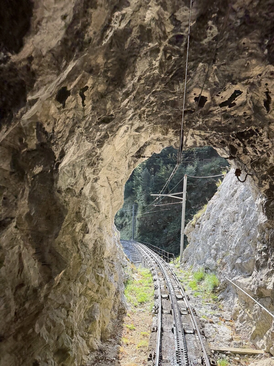 岩をくり抜いたトンネルの出口と、その先へ続く登山鉄道の線路