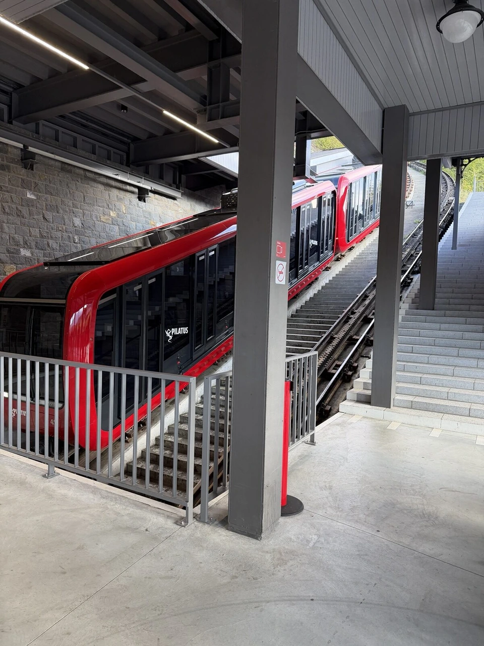 ピラトゥス登山鉄道の赤い車両が斜めのホームに止まっている様子