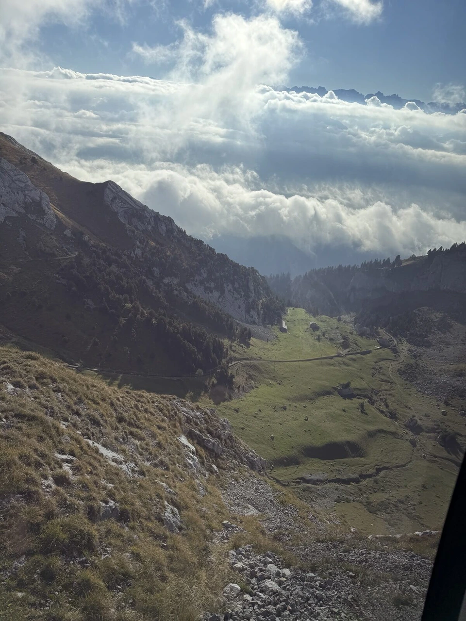 山頂近くの登山鉄道から見下ろした谷と牧草地、雲