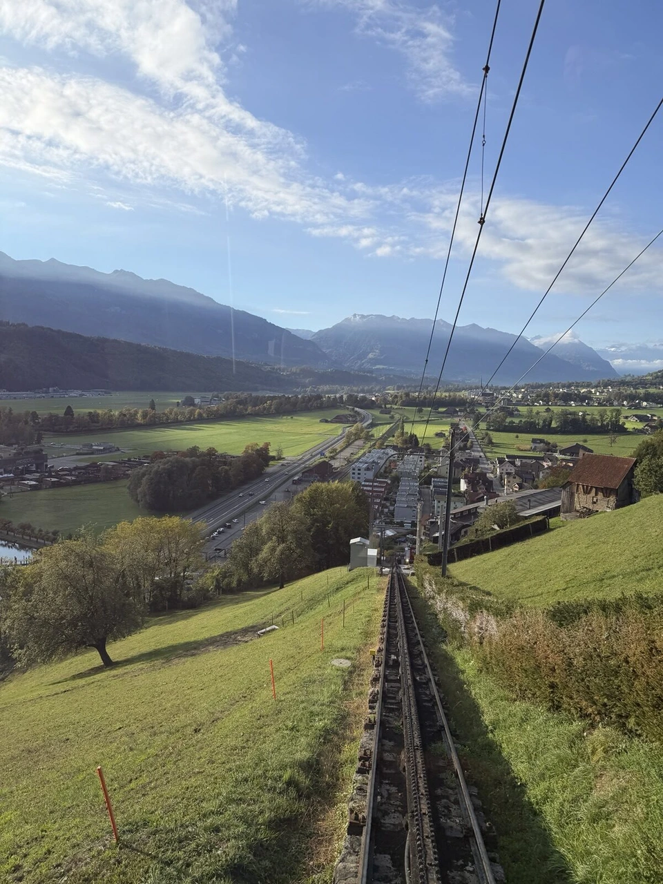 登山鉄道の窓から見下ろした急勾配の線路と牧草地