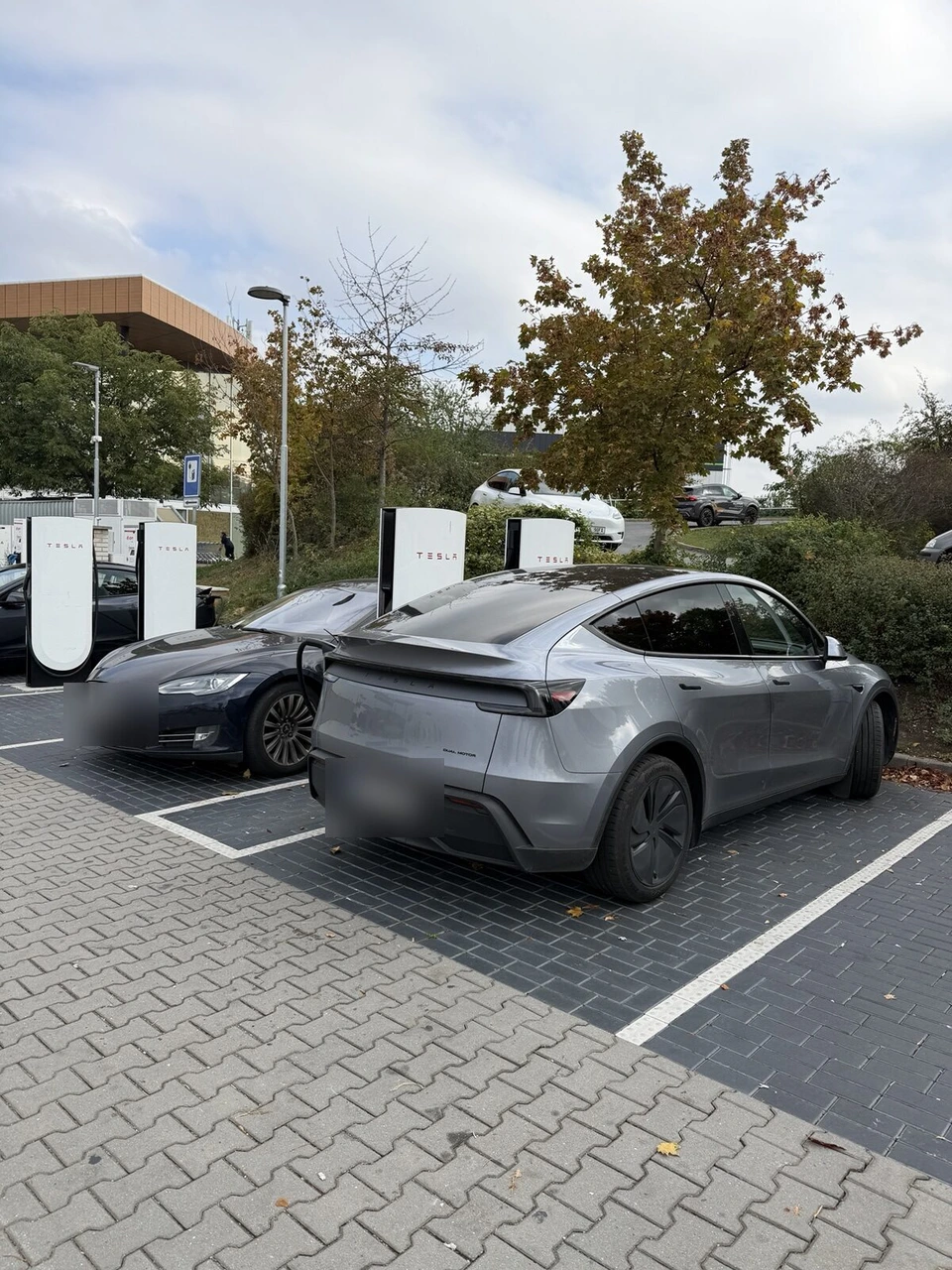 スーパーチャージャーにつないだグレーのテスラ Model Y と白い充電器