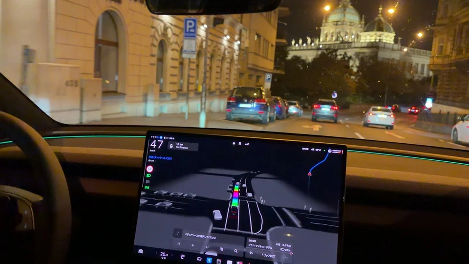 夜のプラハの通りを走るテスラの車内。画面にルートが表示されている