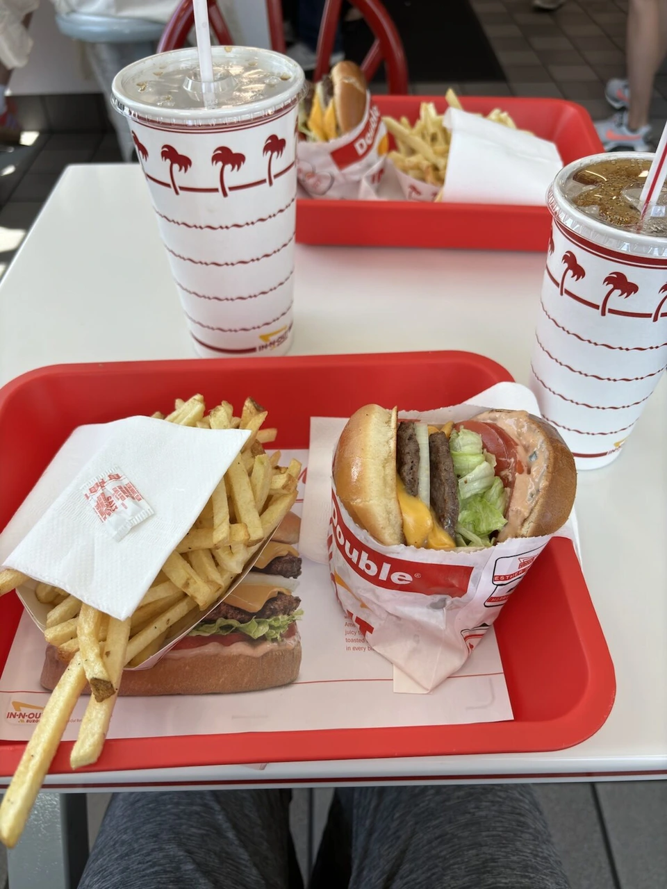 イン・アンド・アウト。赤いトレーに載ったダブルダブルとフライドポテト、ヤシの木柄のカップ