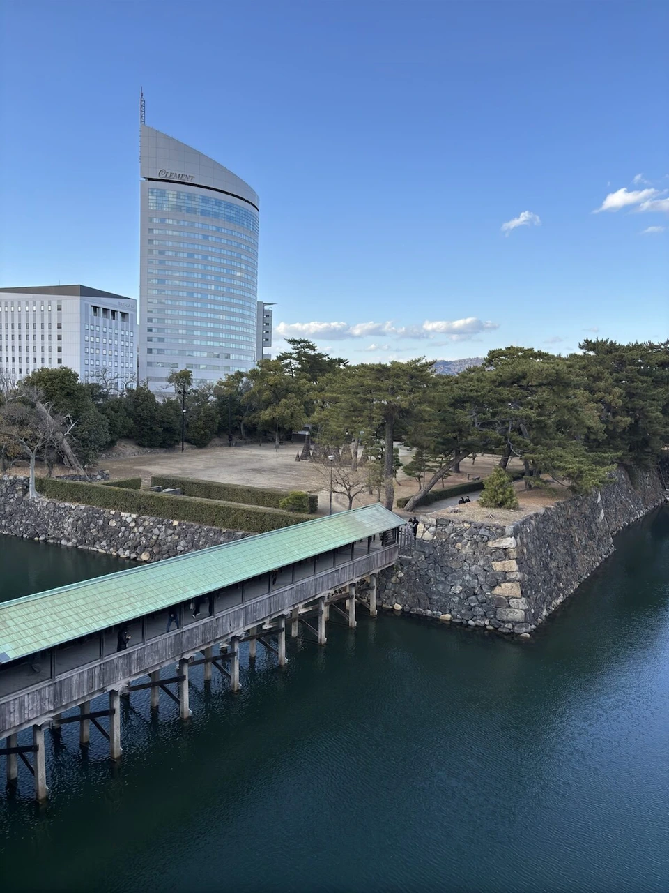玉藻公園の内堀に架かる屋根付きの鞘橋を上から見たところ。奥にサンポート高松の高層ビル