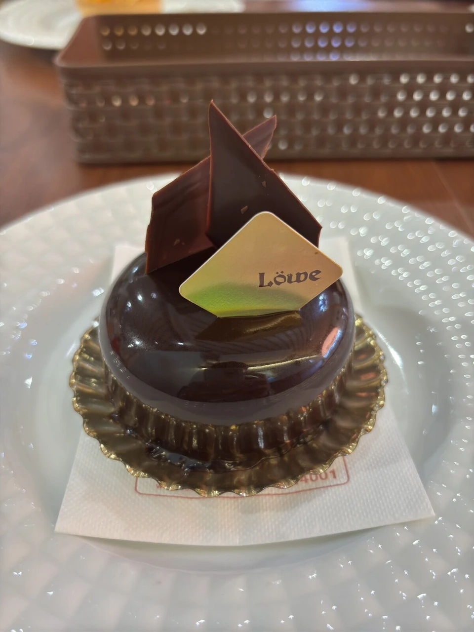 菓子工房ルーヴのチョコレートケーキ。つやのあるドーム形に、Löweと書かれた金色のプレートと板チョコの飾り