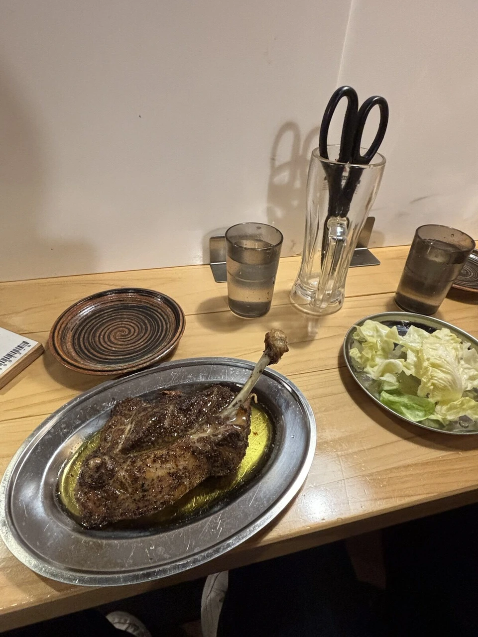高松の店で食べた骨付鳥。銀色の皿に乗った骨付鳥と、キャベツの皿、はさみの入ったグラス
