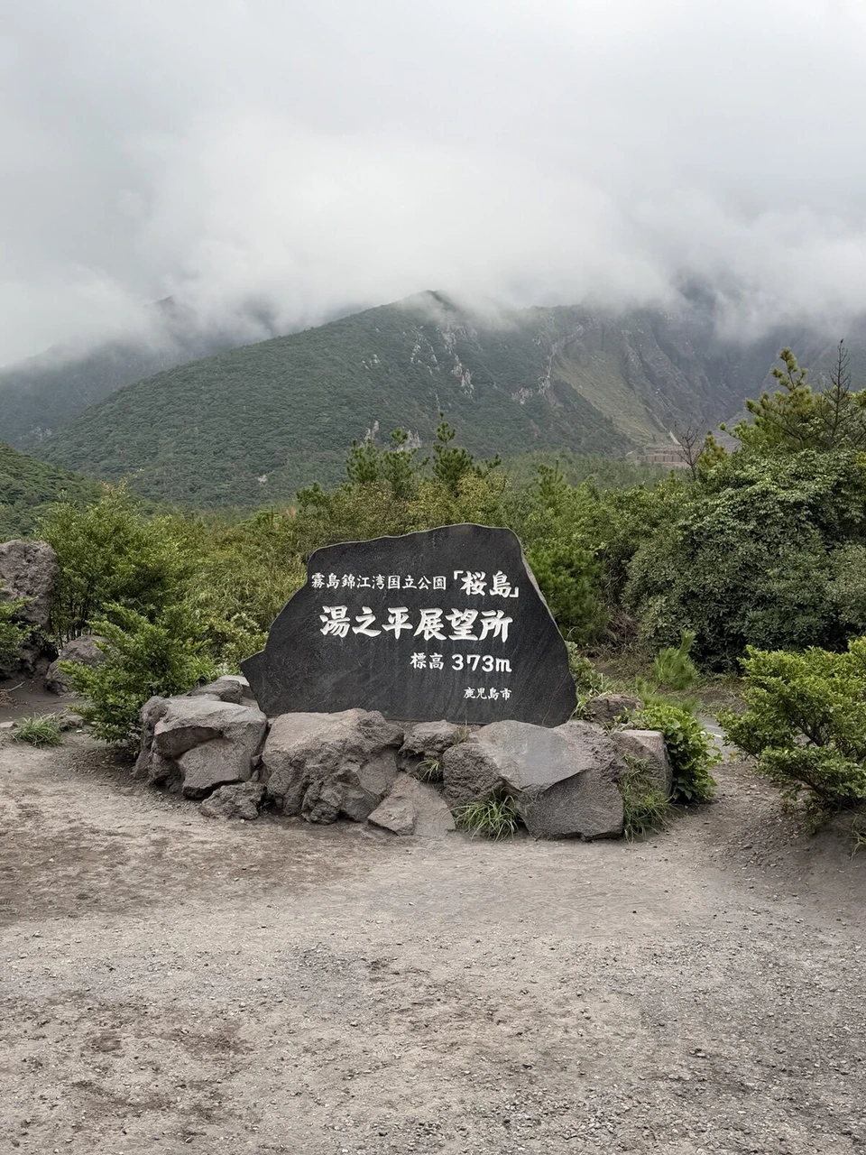 「霧島錦江湾国立公園 桜島 湯之平展望所 標高373m 鹿児島市」と刻まれた石碑。背後の山は雲に隠れている