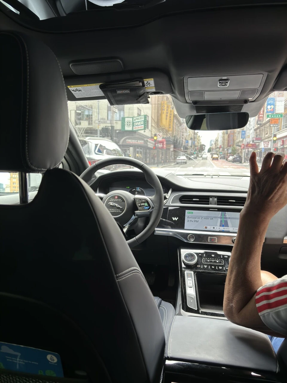 無人タクシーWaymoの車内。誰もいない運転席とハンドル、画面に到着予定の表示