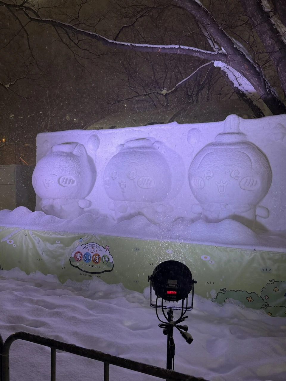 紫色にライトアップされた、3つの顔が並ぶ横長の雪像