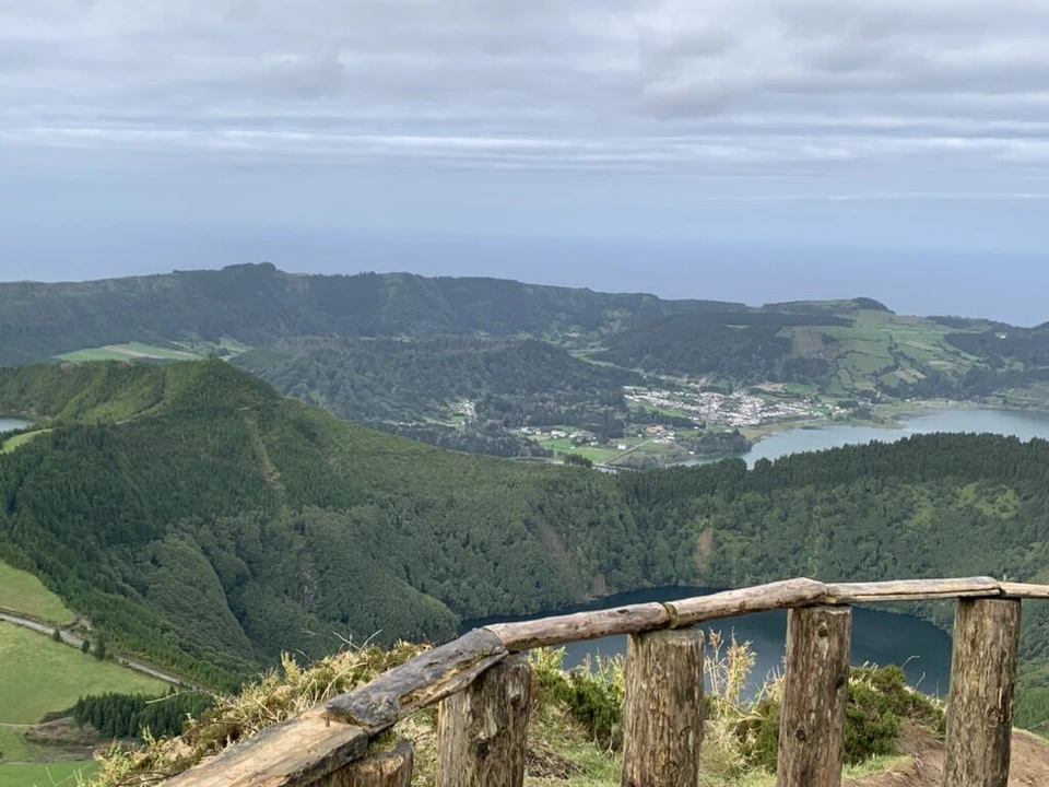 ボカ・ド・インフェルノの木の柵越しに見たセテ・シダーデスのカルデラの湖と村