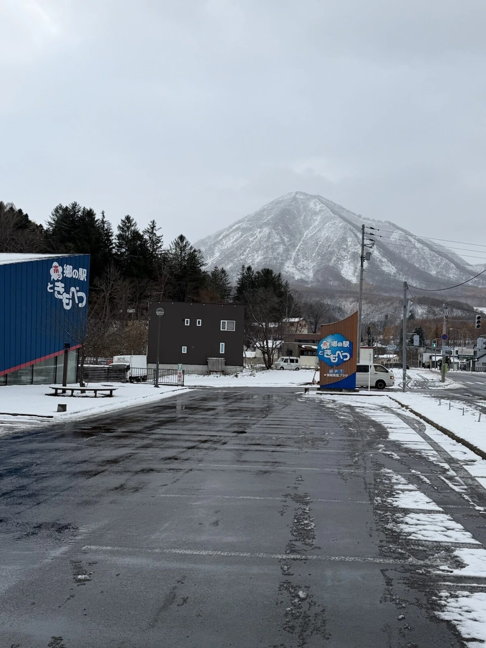 郷の駅ときもべつの青い建物と看板、その奥のとがった雪山