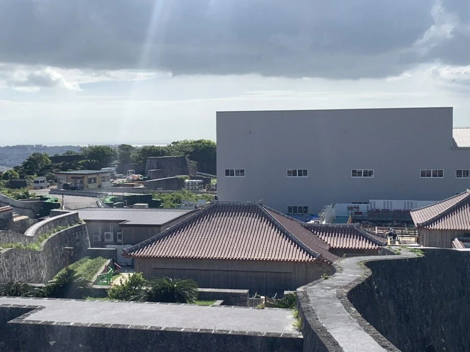 首里城の城壁の上から見た、赤瓦の建物の奥に建つ大きな白い建物