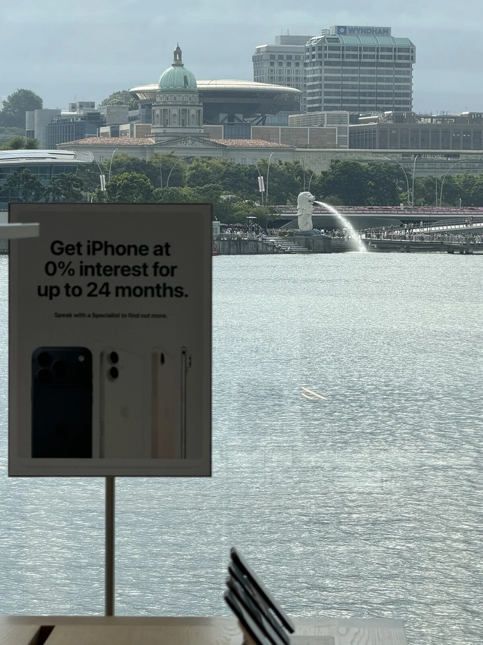 アップルストアのiPhoneの案内板と、窓の外のマーライオンと湾