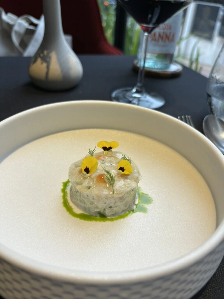 Skillet KLの前菜。黄色い食用花をのせた丸いひと皿と緑のソース