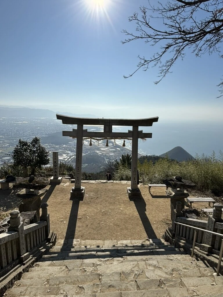 冬の昼過ぎの太陽と枯れ枝、その下の天空の鳥居と灯籠